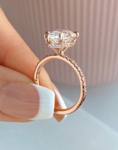 Cushion-cut diamond engagement ring with hidden halo and pavé-set shoulders in rose gold.